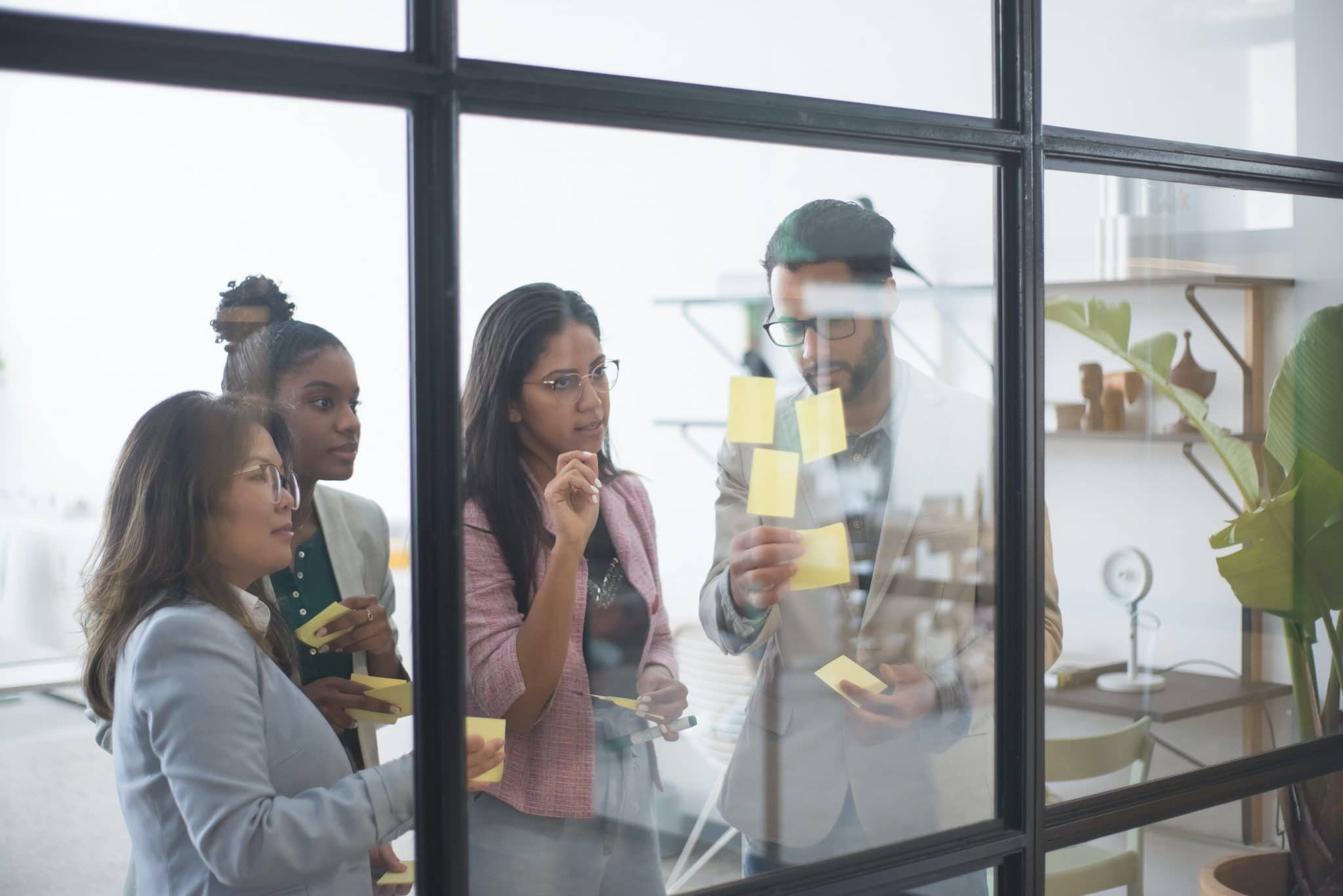 Group of employees planning and placing post-it notes on a wall